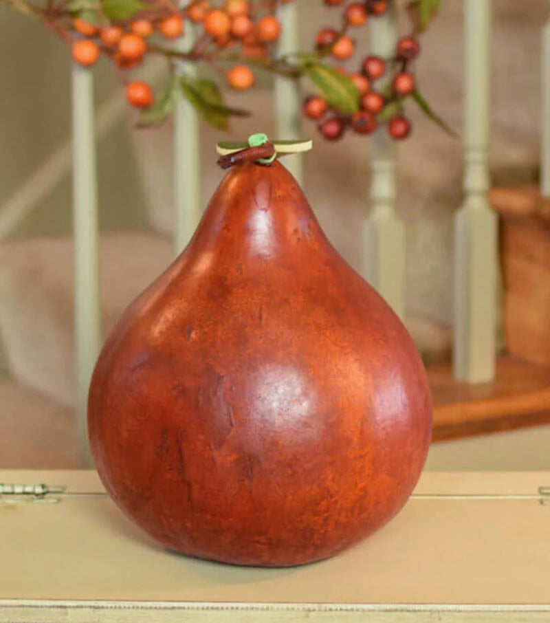 Decorative gourd with a small green stem on a wooden surface with blurred background