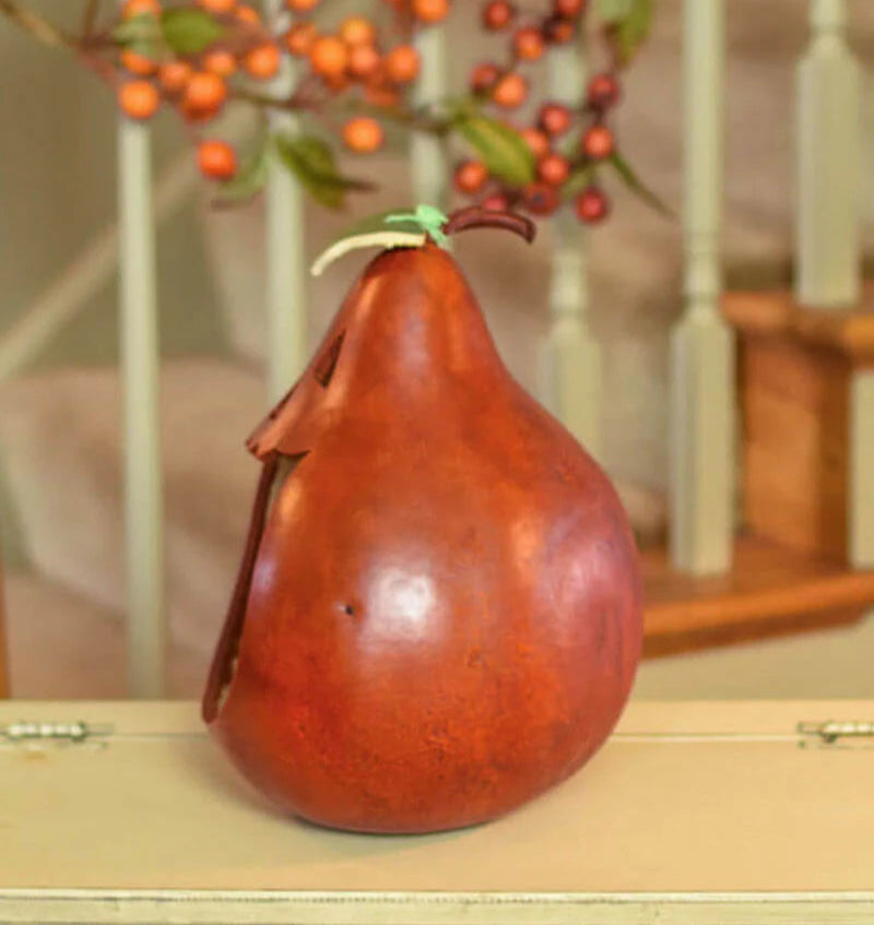 Decorative gourd with a green stem on a wooden surface with blurred background