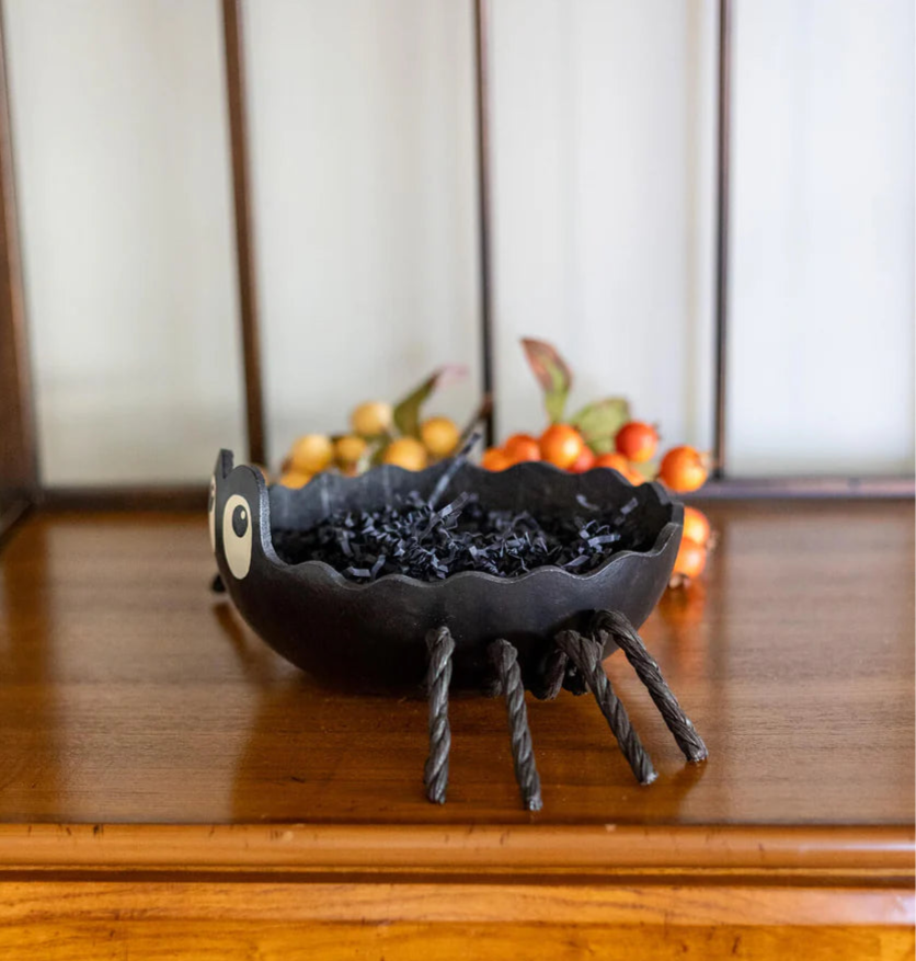 Black spider-shaped decorative bowl on a wooden surface with a blurred background