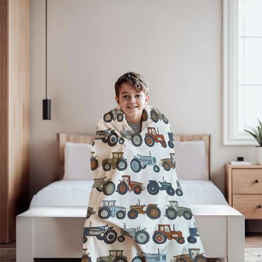 Child wrapped in a blanket with tractor pattern in a bedroom