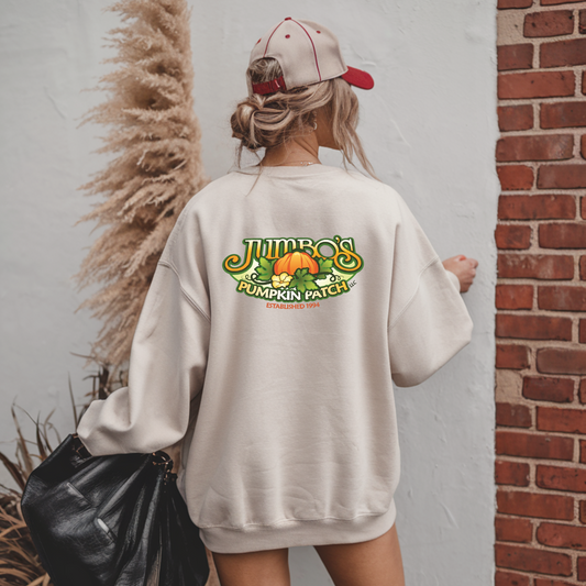 Person wearing a beige sweatshirt with 'Jumbo's Pumpkin Patch' design, standing against a brick wall.