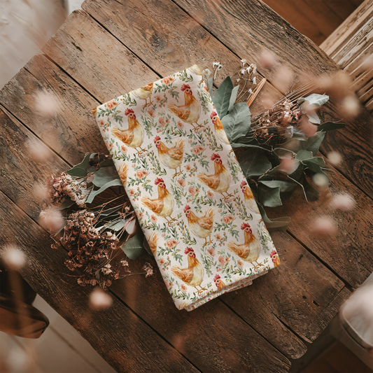 Floral patterned towel with chickens on a wooden surface with plants